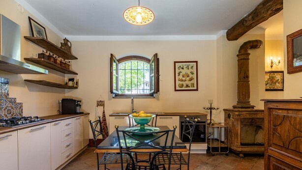 Une cuisine équipée d’une table à manger, de chaises, d’une cuisinière et d’une fenêtre dont le volet est ouvert.