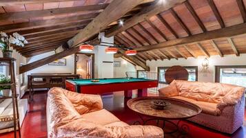 A billiards room with a pool table, two sofas, and a small table with a decorative item.