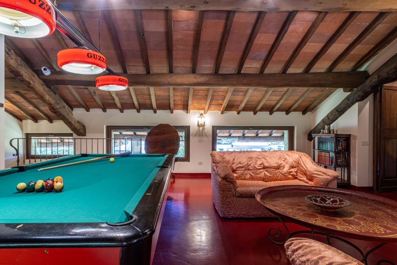A pool table with balls, a sofa, and a table with a decorative bowl.