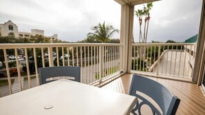 A balcony with a table and chairs, overlooking a street with cars and a building. - 2BR Villa at Holiday Inn Club Vacations Cape Canaveral Beach Resort (Cape Canaveral)