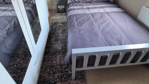 Ein Schlafzimmer mit Bett, Nachttisch, Kommode und Spiegel.