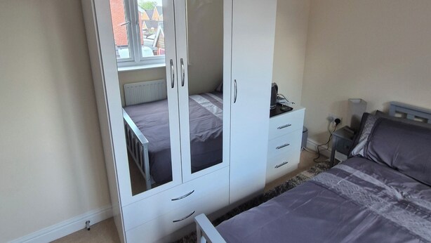 Ein Schlafzimmer mit Etagenbett, Kleiderschrank mit Spiegel und Nachttisch.