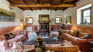 A traditional living room with a fireplace, two sofas, a coffee table, and a painting on the wall. - Welcome to Villa Harmonia, a magnificent historic residence that has been carefully restored to preserve all the authentic charm of traditional Piedmontese farmhouses, combining elegance, comfort, and a timeless atmosphere.Nestled within more than 10,000 (Dormelletto)