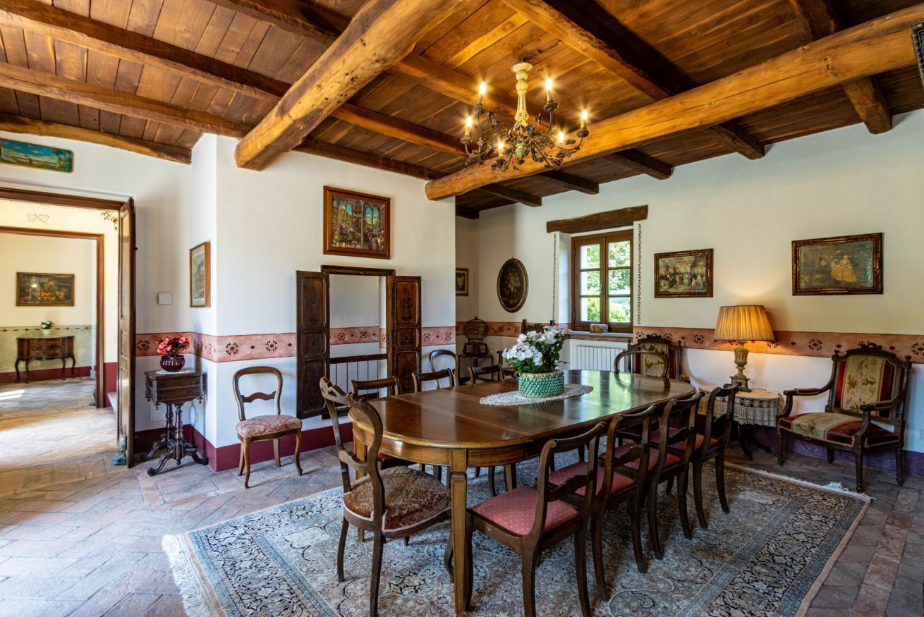 Une salle à manger avec une table en bois, des chaises et un lustre.