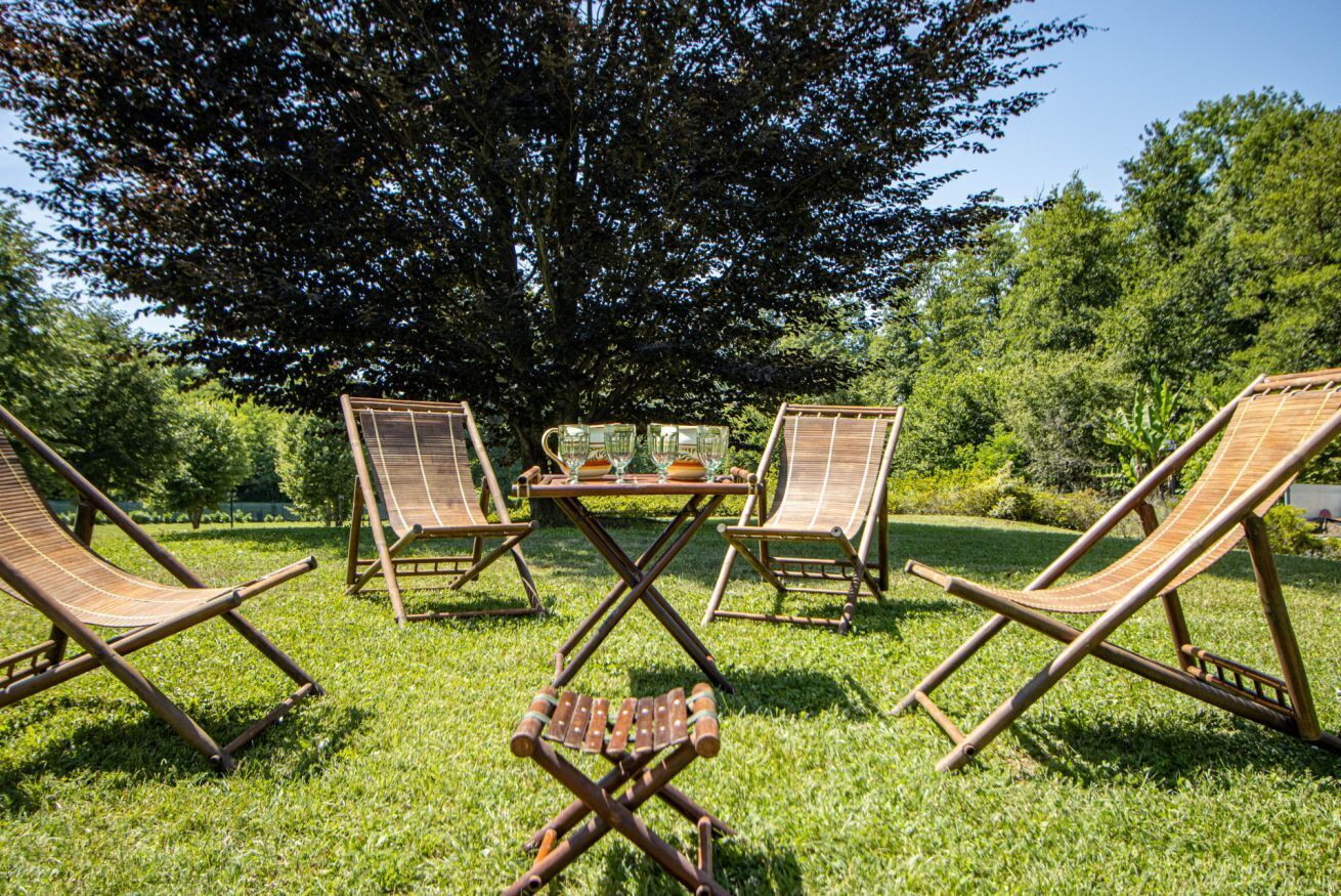 Een gazon met een terras, vier lounge fauteuils en een bijzettafeltje met drankjes.