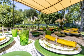 Un área de comedor al aire libre con vajilla verde y un toldo amarillo.