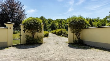 A gravel driveway leading to a gated entrance with a clear sky above.