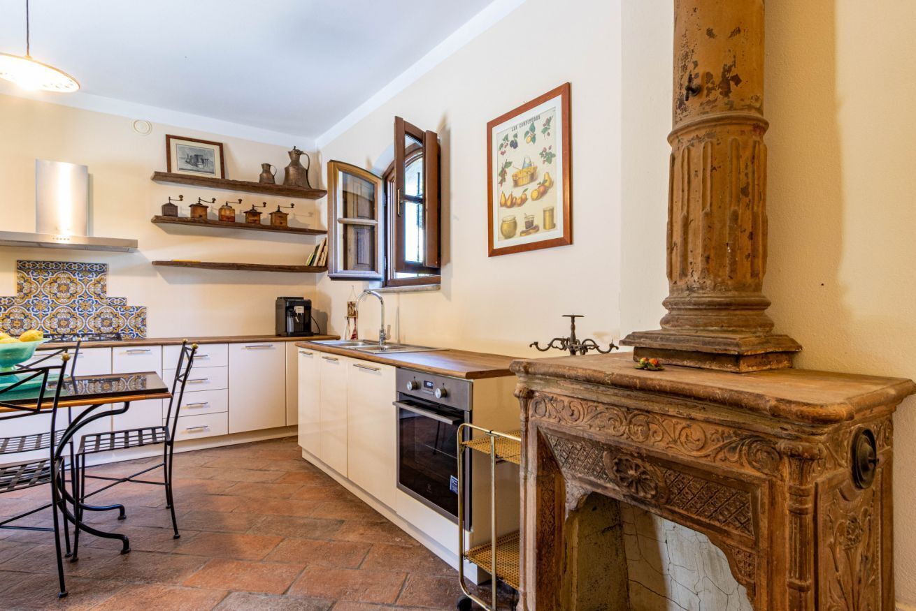 A kitchen with a stove, oven, sink, and decorative shelves.