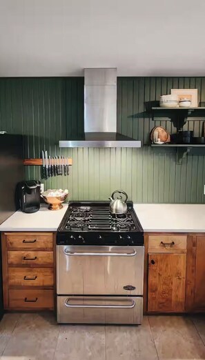 A kitchen with a stainless steel stove, a kettle, and a coffee maker.