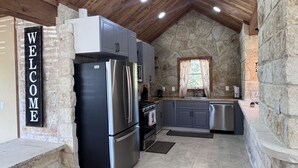 Una cocina con paredes de piedra, un letrero de bienvenida y electrodomésticos modernos.