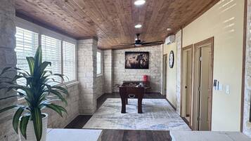 Una habitación con techo de madera, paredes de piedra, una mesa de fútbol de mesa y una planta en maceta.