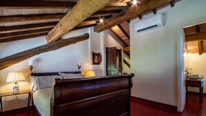 Une chambre avec un plafond en bois, un lit doté d’une tête de lit, des lampes de chevet, une table de chevet et un plancher en bois.