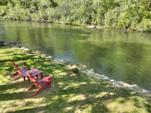 A riverside view with a grassy area and a red chair. - Time Out On The Toccoa | Blue Ridge, GA (Blue Ridge)