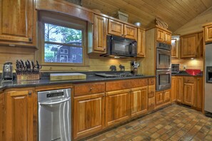 A kitchen with wooden cabinets, a stainless steel dishwasher, a microwave, a stove, and a refrigerator. - Time Out On The Toccoa | Blue Ridge, GA (Blue Ridge)