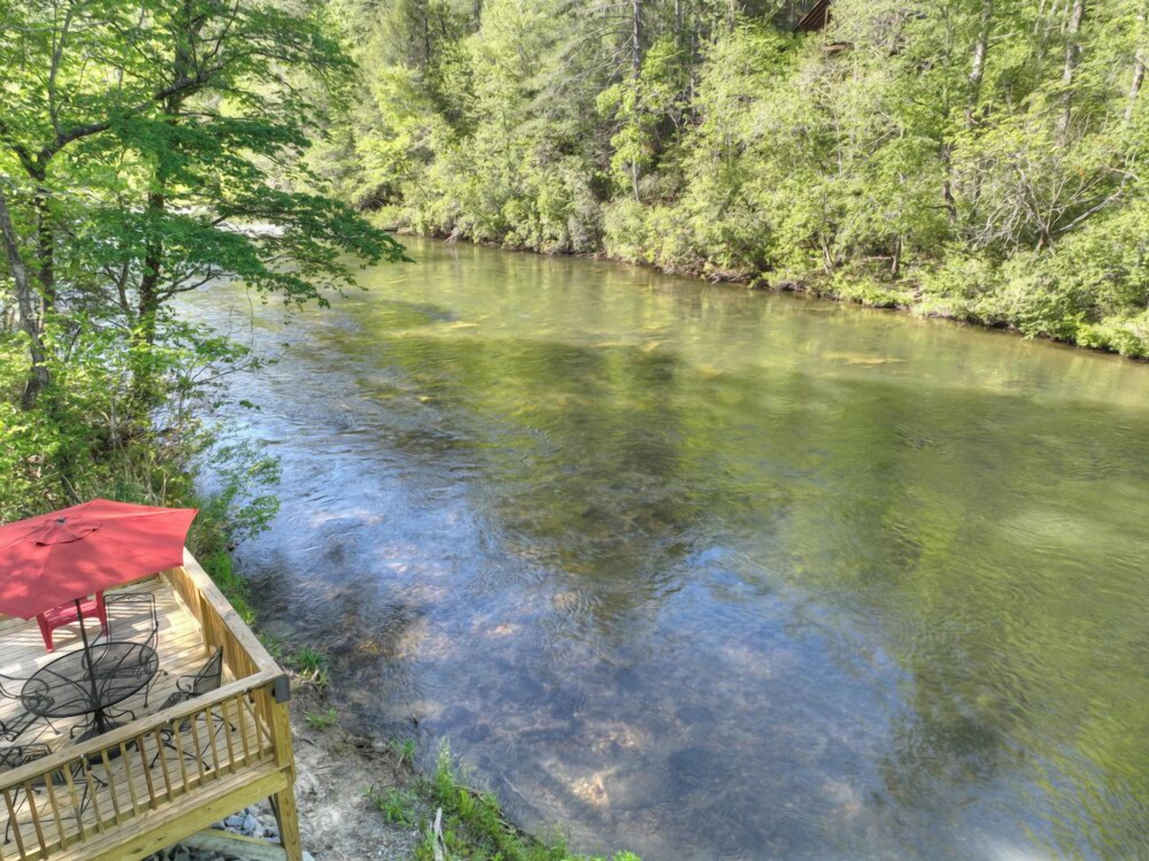 A wooden deck with outdoor furniture overlooking a river.