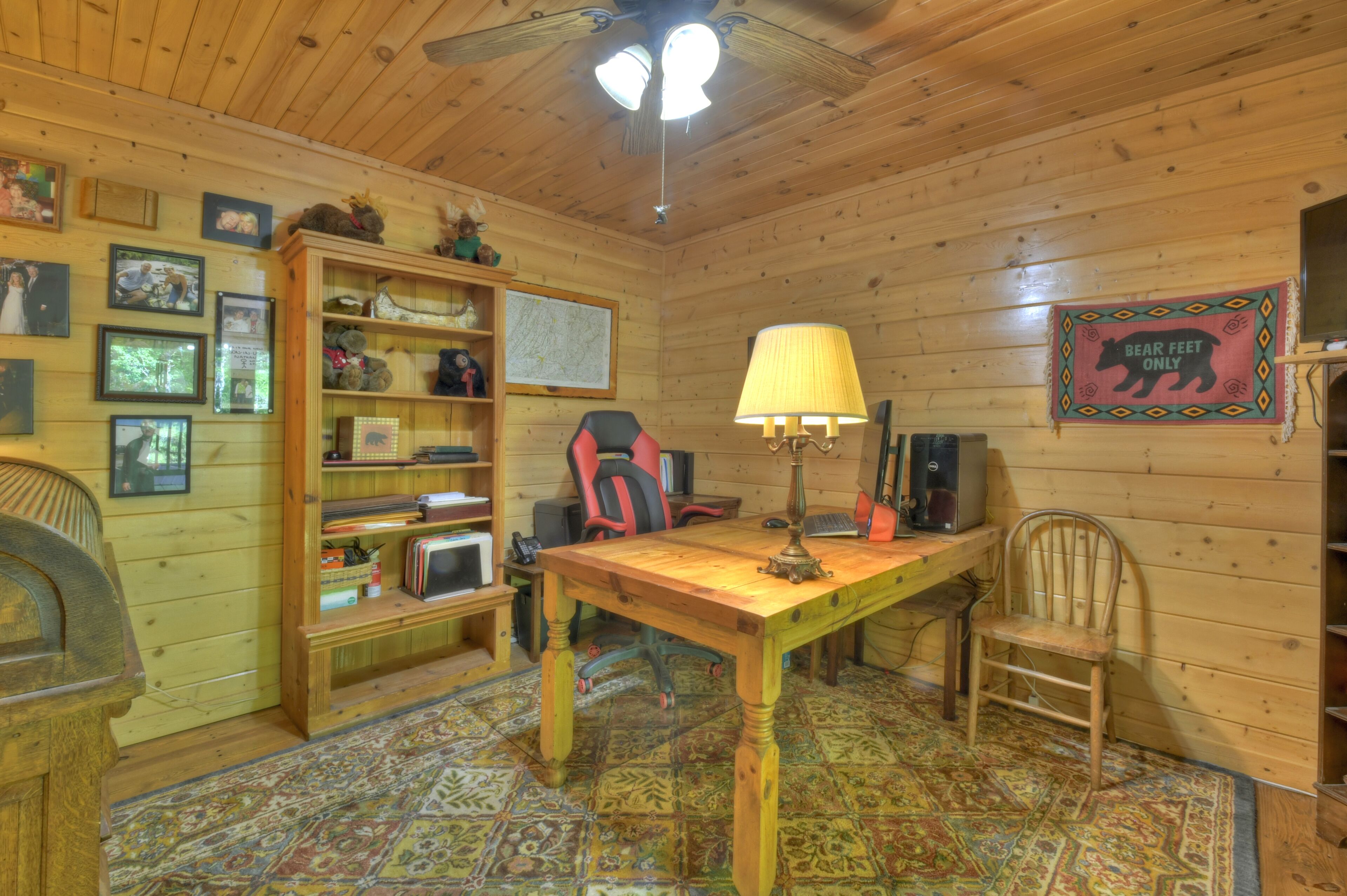 A cozy cabin interior with a wooden desk, chair, and a map on the wall.