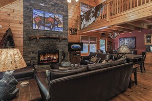 Ein Urlaubsdomizil mit Kamin aus Stein, Ledersitzmöbeln und einem Fernseher.
