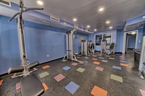 Ein Fitnessraum mit Trainingsgeräten, einem Spiegel und einem farbenfrohen Boden.