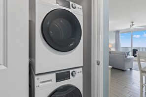 A stacked washer and dryer unit with a control panel, located in a room with a view of a balcony. - Shores of Panama 721~Sleeps 8 (Panama City Beach)