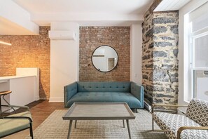 Un salon moderne avec un canapé bleu, un miroir rond et une table basse.