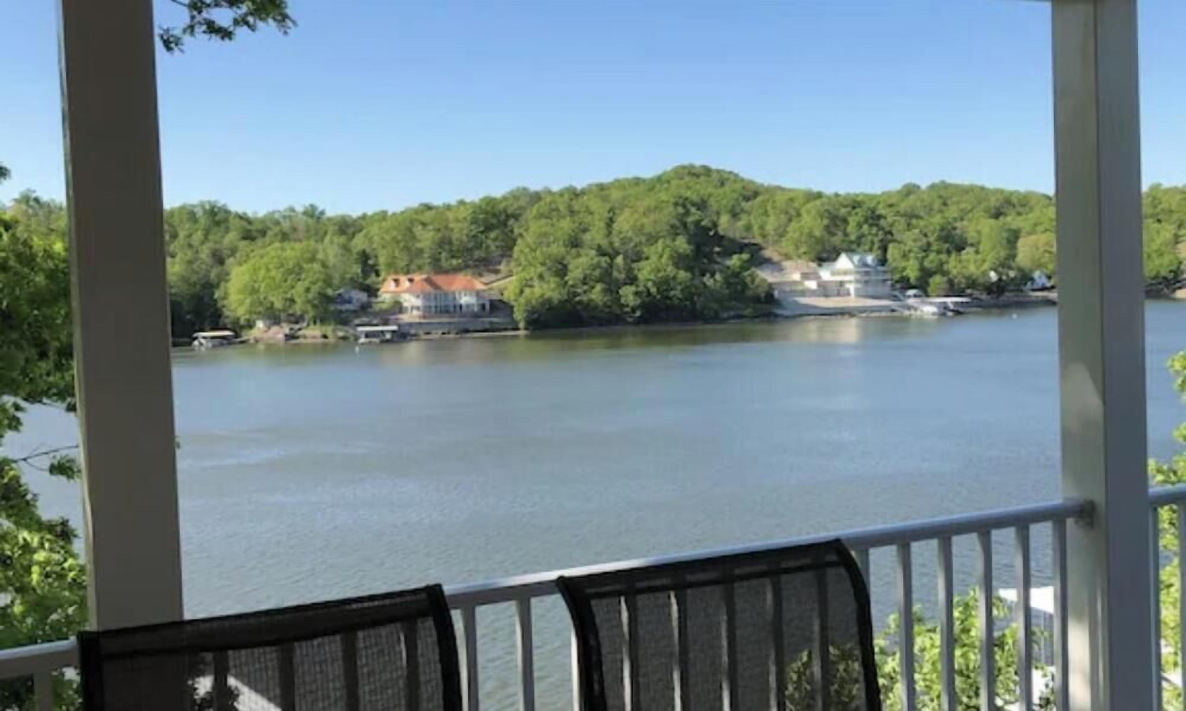 A view from a balcony overlooking a lake with buildings on the opposite shore.