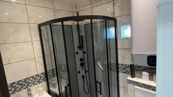 Une salle de bain moderne avec une douche à parois de verre, un lavabo, des toilettes et une poubelle.
