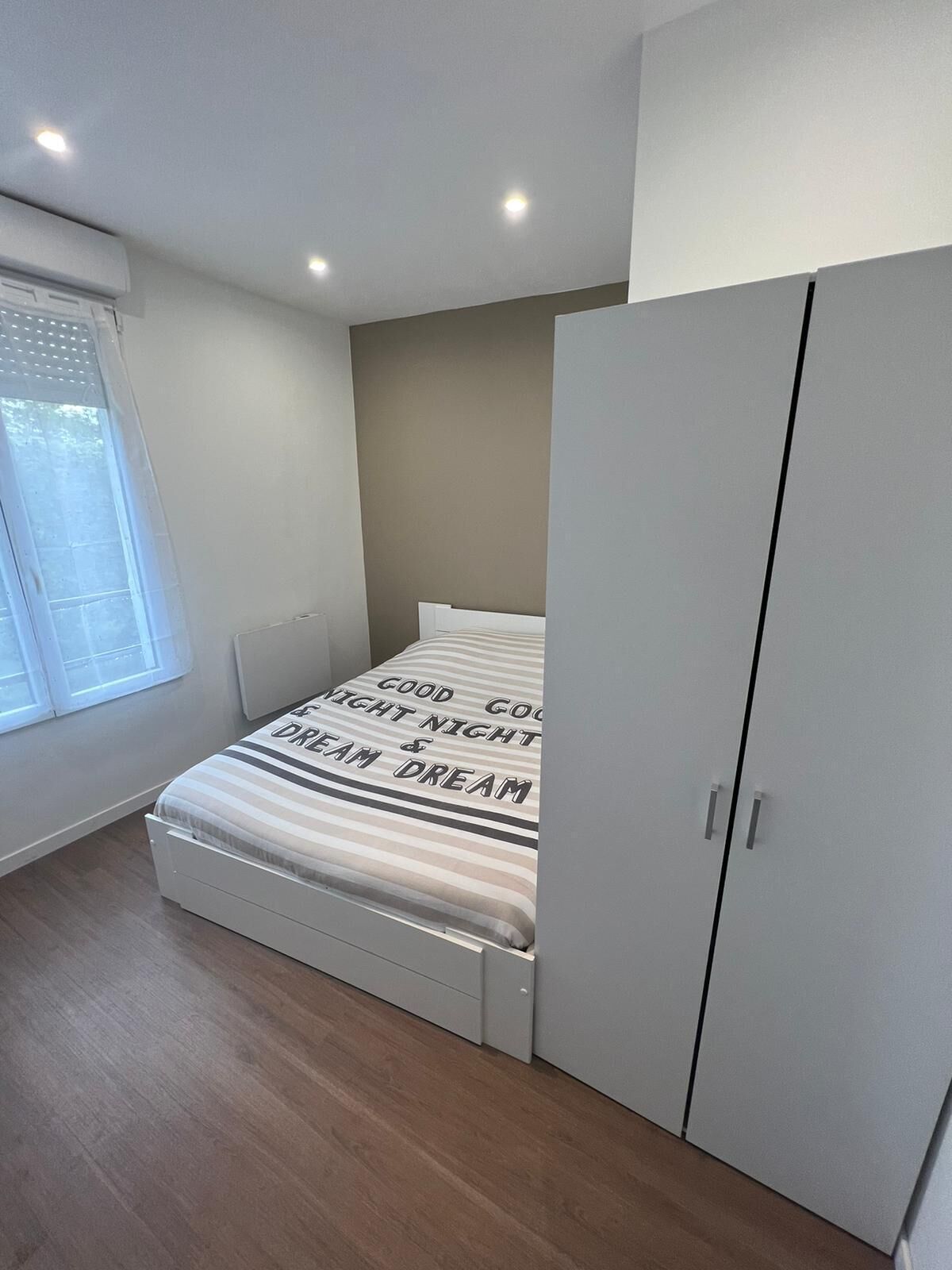 Une chambre à coucher avec un lit, une armoire et une fenêtre.