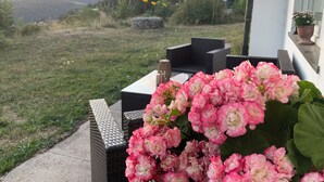 A patio with outdoor furniture, a flower arrangement, and a view of a natural landscape.