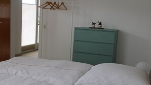 Ein Schlafzimmer mit einem Bett, einem Schminktisch und einem Fenster mit Jalousien.