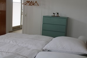 A bedroom with a bed, a dresser, and a window with blinds. - Waldglück Vacation Rental (Herrischried)