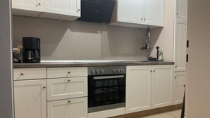Eine Küche mit weißen Schränken, einem Backofen und einer Kaffeemaschine.