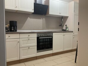 A kitchen with white cabinets, a built-in oven, and a coffee maker. - Waldglück Vacation Rental (Herrischried)
