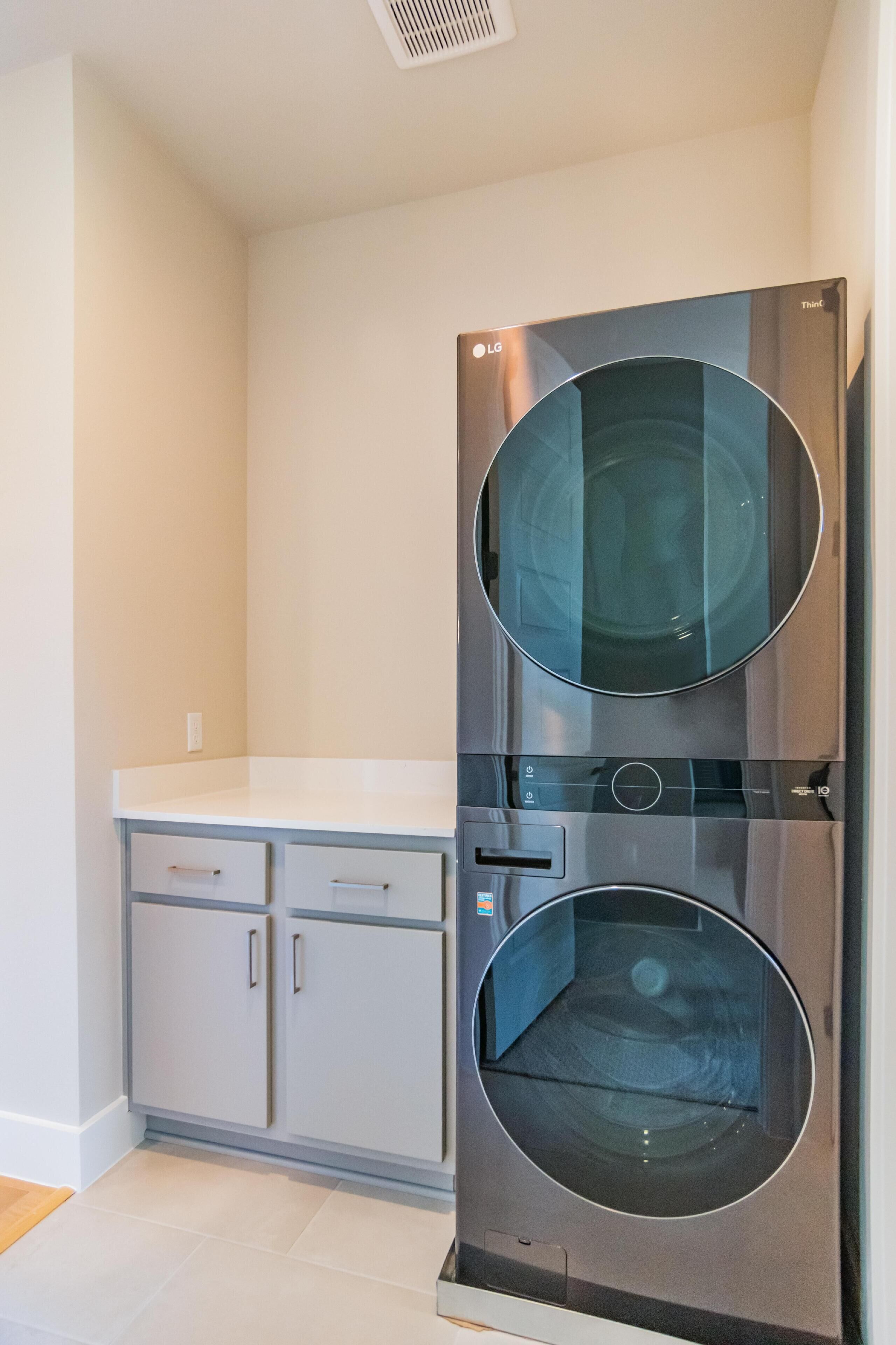 A modern kitchen with a double stainless steel oven, a white countertop, and grey cabinets.
