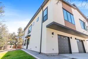 Ett modernt hus i två våningar med ett garage, en välskött gräsmatta och ett trästaket.