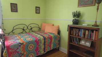 A room with a bed, a bookshelf, and two framed pictures on the wall.
