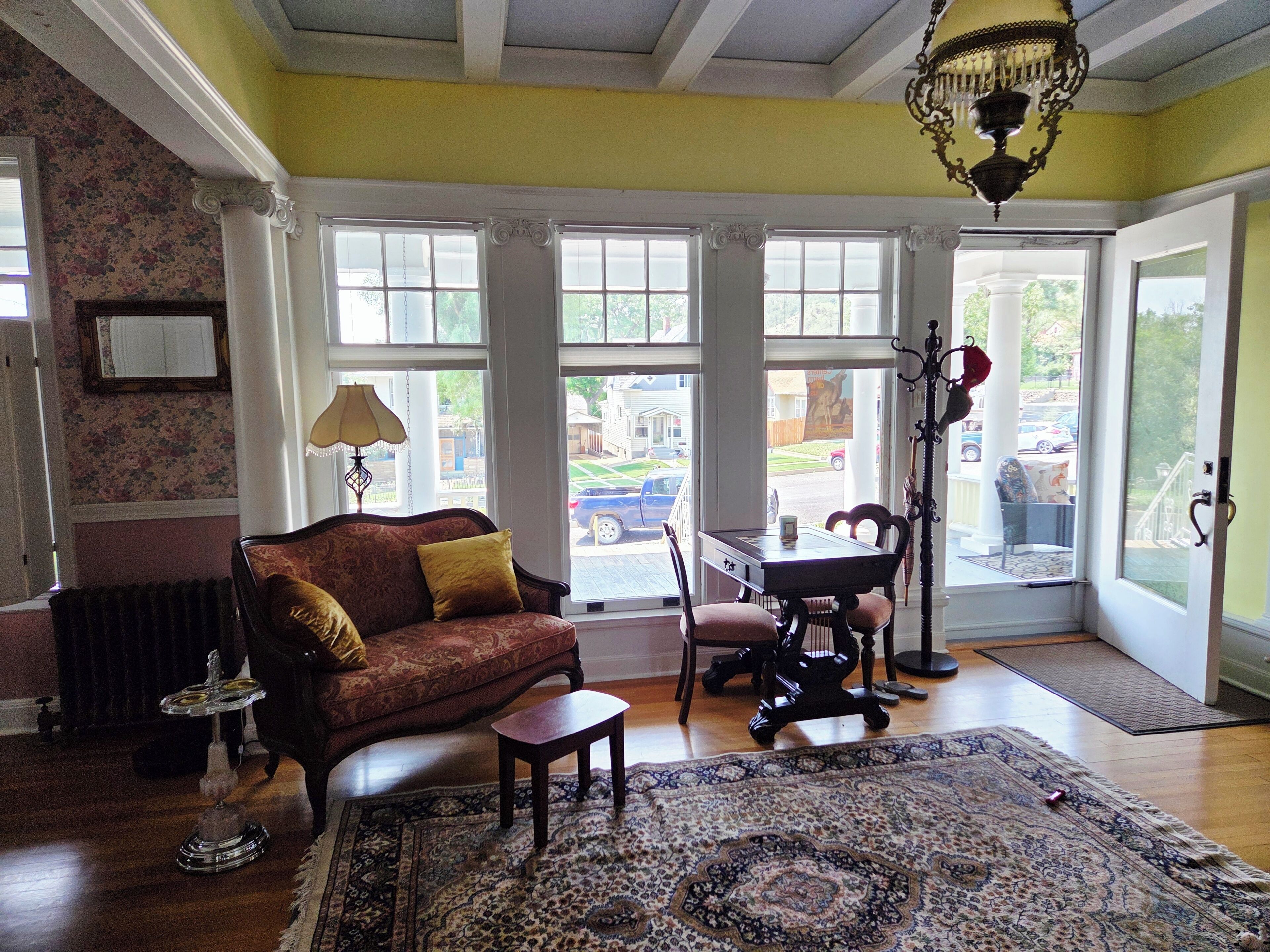 A room with a sofa, a table, chairs, a rug, and a chandelier.