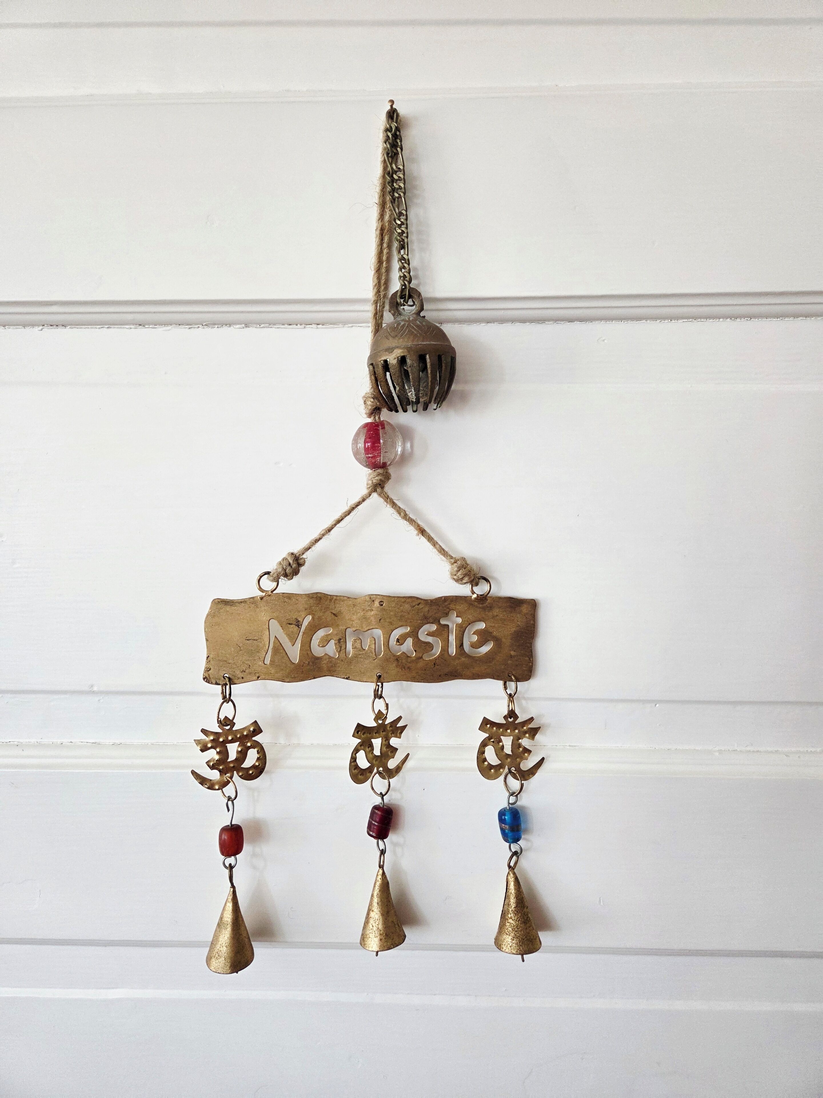 A decorative hanging with a nameplate and three hanging ornaments.