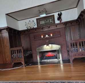 Una habitación con chimenea de ladrillo, muebles de madera y una alfombra estampada.