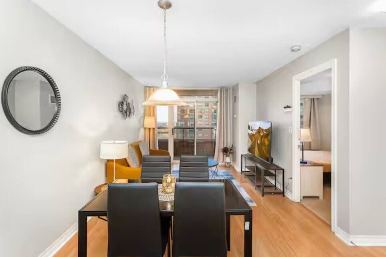 Een moderne woonkamer met een eethoek, een grote spiegel en een schilderij aan de muur.