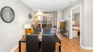 Een moderne woonkamer met een eethoek, een grote spiegel en een schilderij aan de muur.