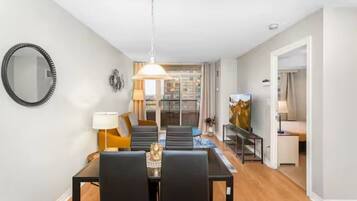 Een moderne woonkamer met een eethoek, een grote spiegel en een schilderij aan de muur.