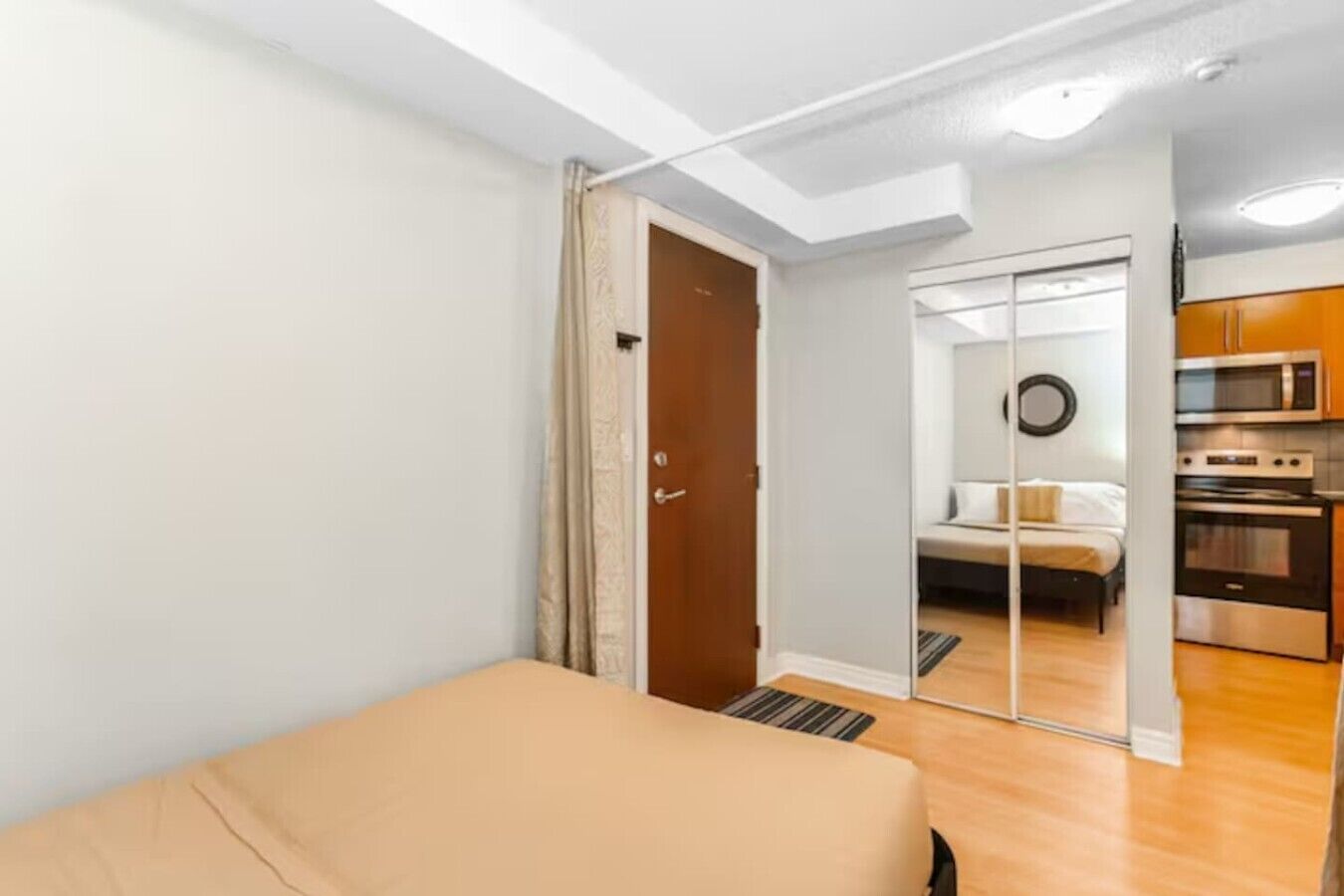 Een slaapkamer met een bed, een deur naar een badkamer en een kitchenette met oven en magnetron.