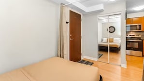 Een slaapkamer met een bed, een deur naar een badkamer en een kitchenette met oven en magnetron.