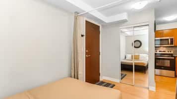 Een slaapkamer met een bed, een deur naar een badkamer en een kitchenette met oven en magnetron.
