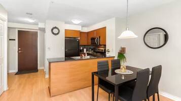 A modern kitchen with wooden cabinets, a black refrigerator, and a dining area with a black table and chairs.
