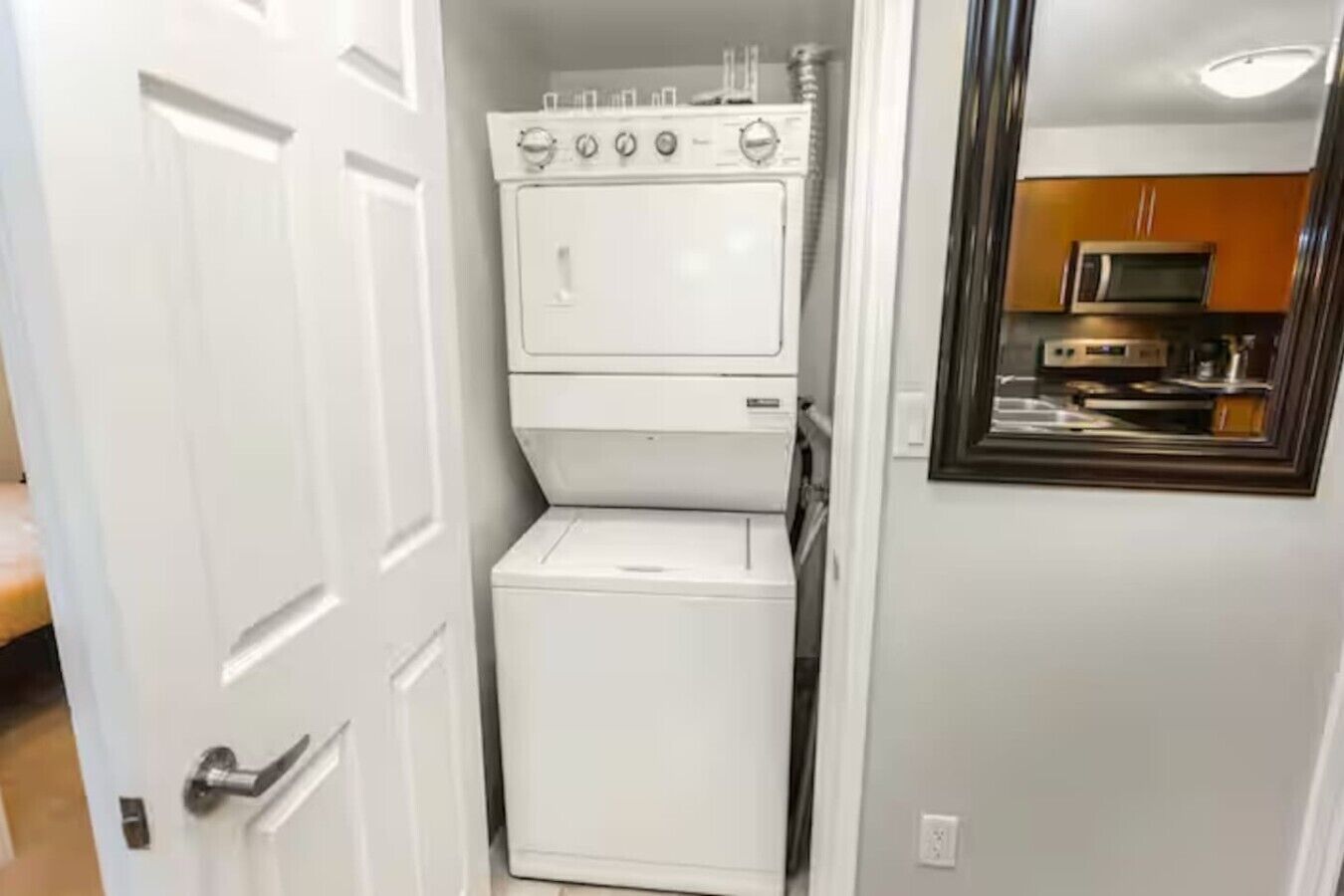A compact laundry room with a washer and dryer, a microwave, and a small kitchen area.