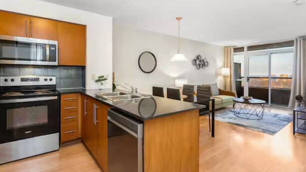 Een moderne keuken met een inbouwoven en magnetron, een eetgedeelte met een ronde tafel, en uitzicht door een grote schuifpui.