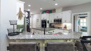 A kitchen with white cabinets, a granite countertop, and a stainless steel range hood. - Midland Poolside Family Oasis (Columbus)