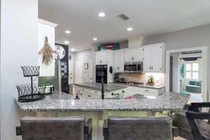 A kitchen with white cabinets, a granite countertop, and a stainless steel range hood.