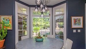 A dining area with a round table, chairs, a potted plant, and artwork on the walls. - Midland Poolside Family Oasis (Columbus)